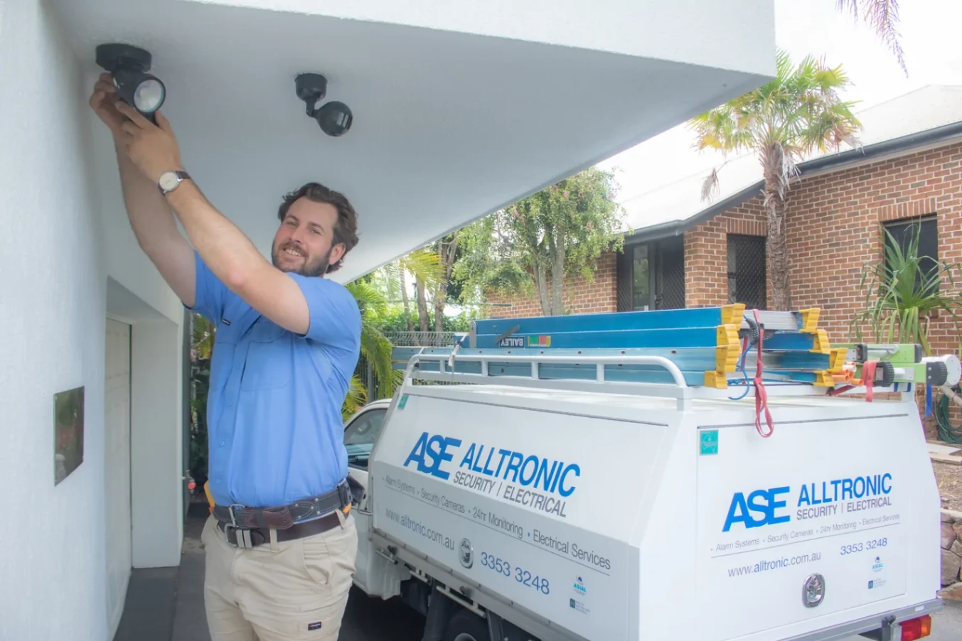 Technician installing a security camera under eaves