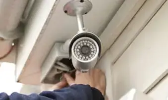 security camera being installed under a roof eve