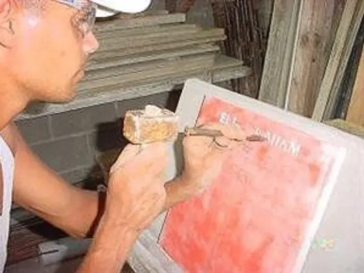 Stone mason engraving a stone memorial using a hammer and chisel