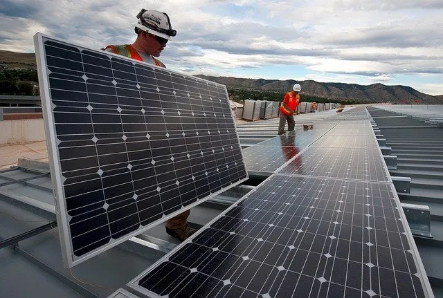 Powerix solar technicians carrying large solar panels to install in a large solar system installation.