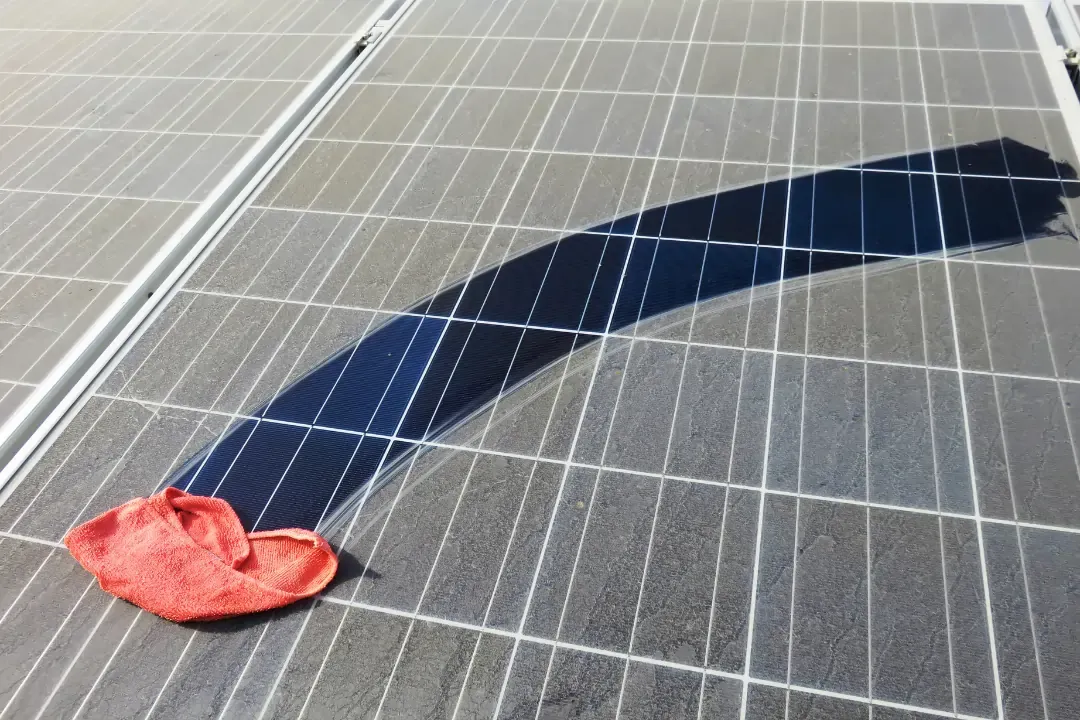 Dirty solar panels prior to solar panel cleaning with clean wiping away a section showing the extent of the dirt & dust build up