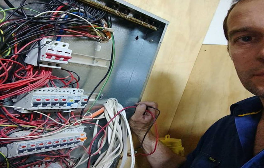 Powerix electrician holding wires from switchboard during electrical inspection and switchboard upgrade for new electrical vehicle charging station installation and solar system installation