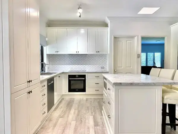 Kitchen designed and installed by Haddons. Sleek cabinetry with black handles, marble benchtop on kitchen island and stainless steel sink to finish.