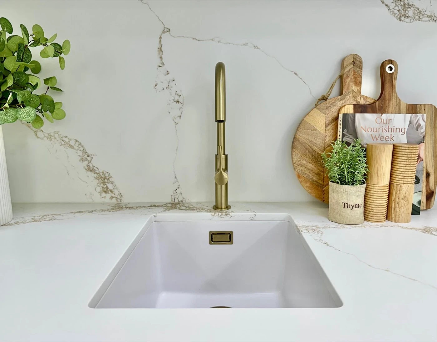 Undermount sink with brushed brass tapware on a stone benchtop