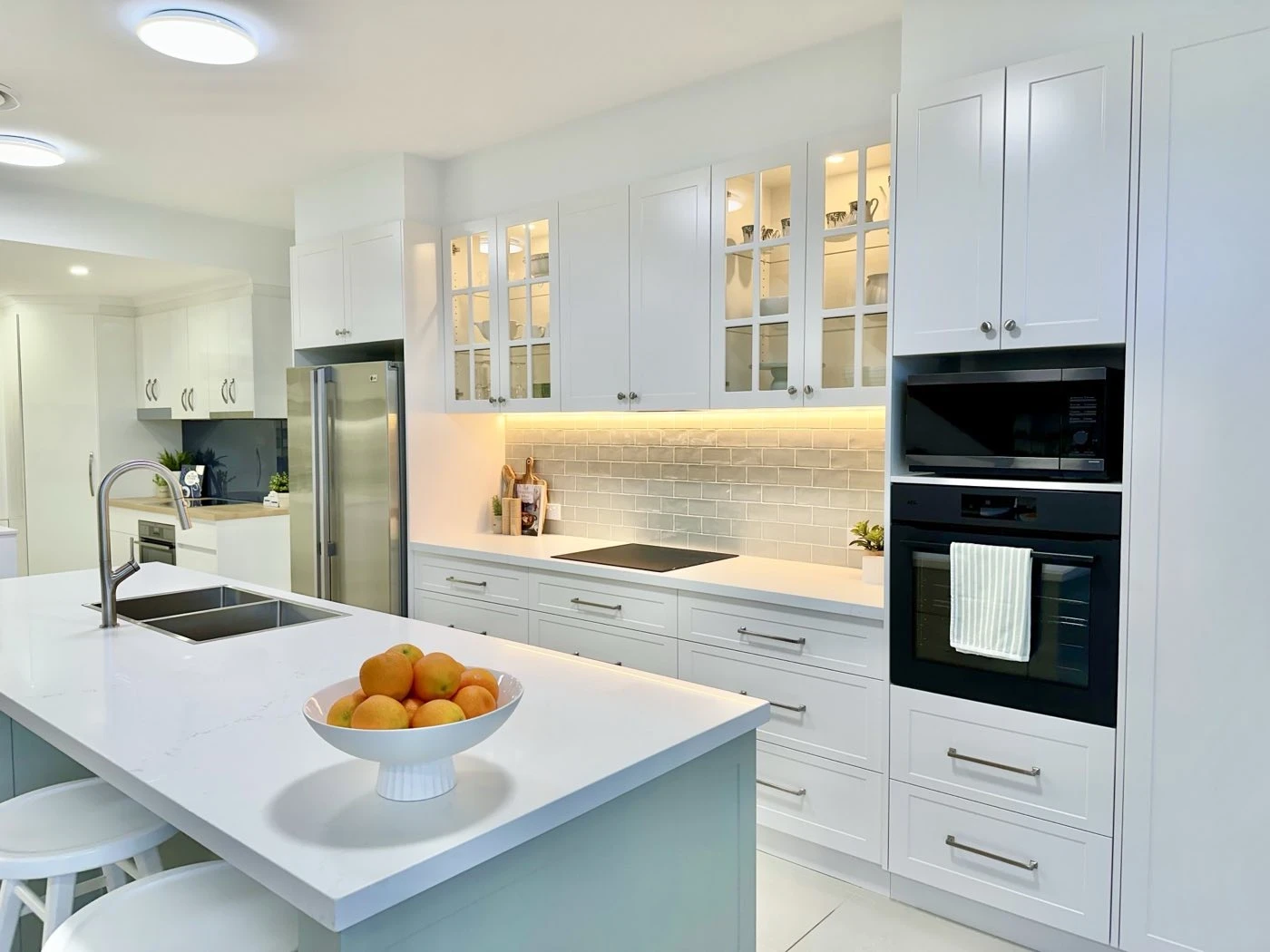 Display kitchen with wall oven tower, glass overheads and stone island