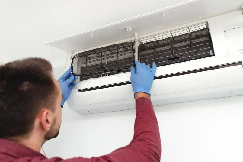 technician cleaning an AC unit