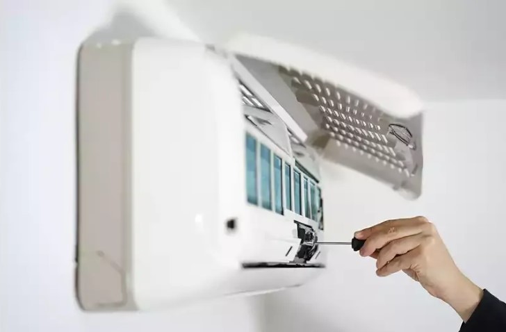 Air Conditioning Unit Being Repaired by HVAC Technician with Screwdriver