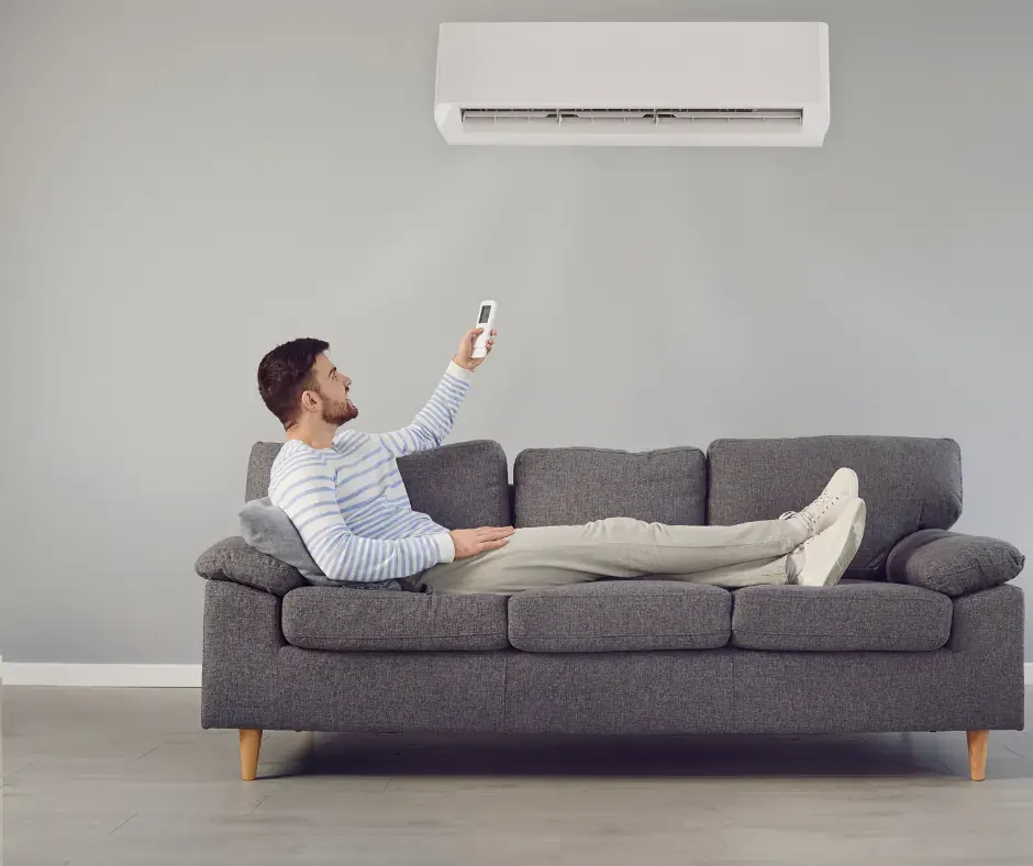 Split System Air Conditioner Unit cooling lounge with man sitting on settee