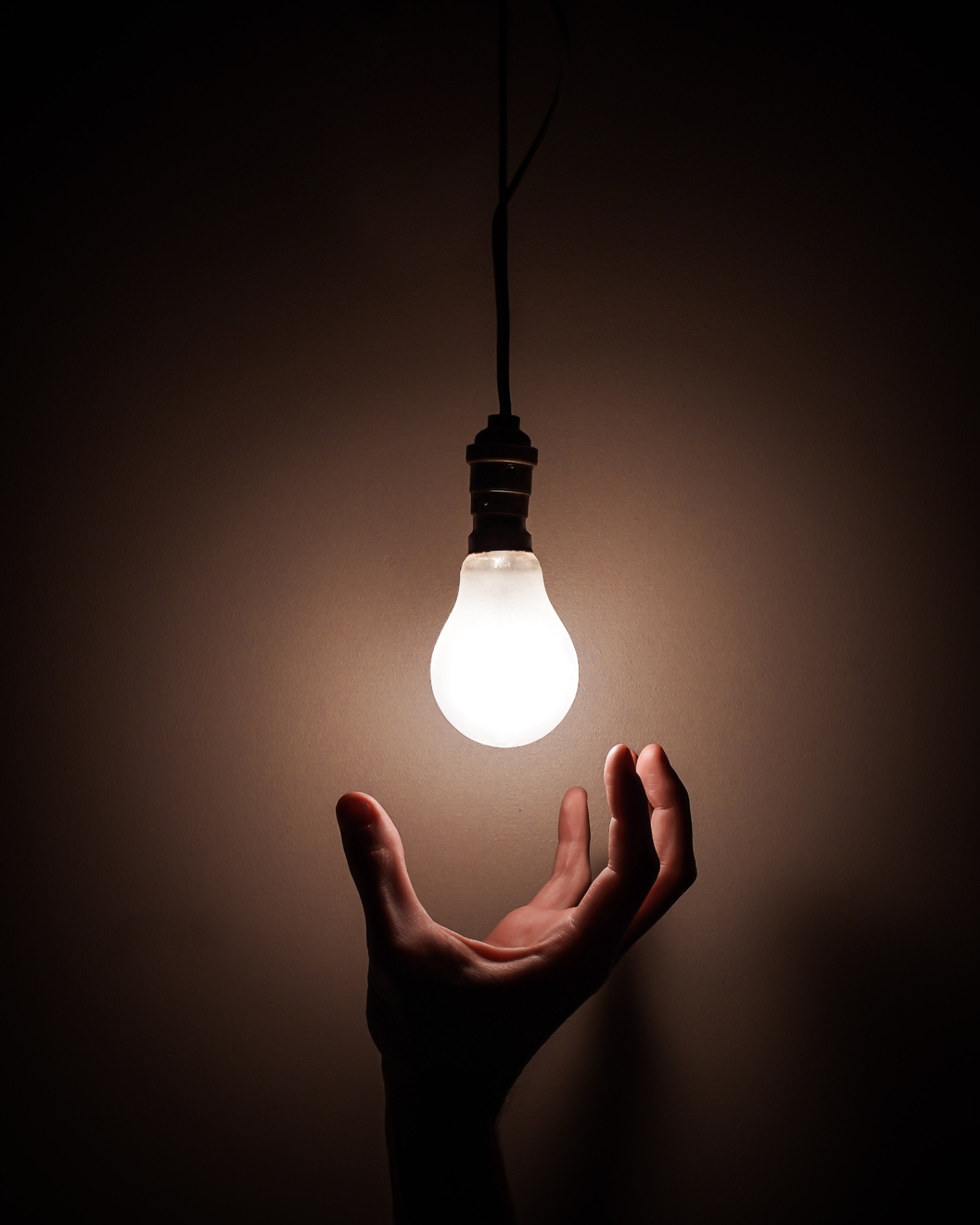 Light bulb with hand reaching to change it