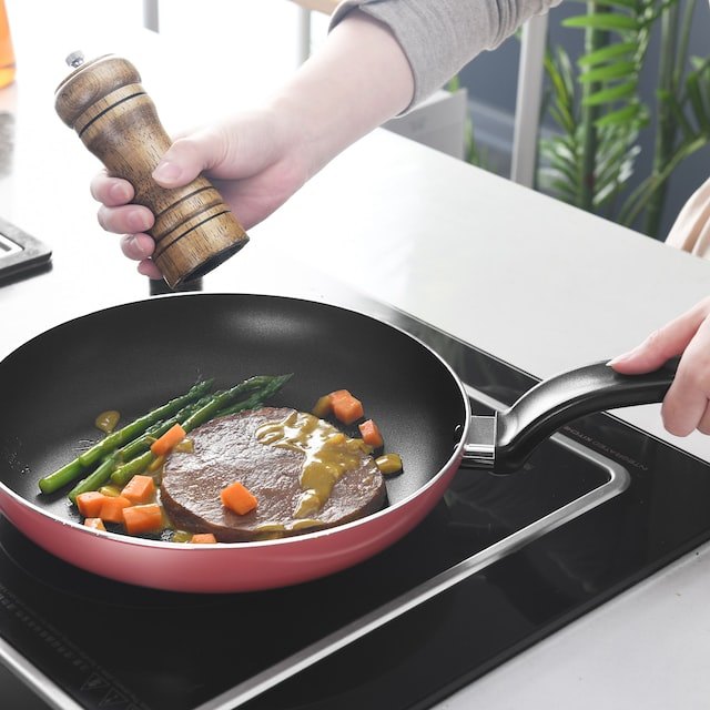 Cooking food in frying pan on electric cooktop