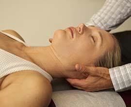 chiropractor holding each side of persons neck to check alignment during chiropractic treatment