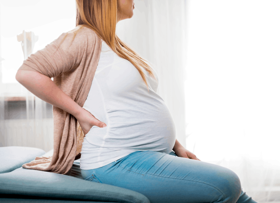 Pregnant woman holding her aching back at naturopathy appointment. 