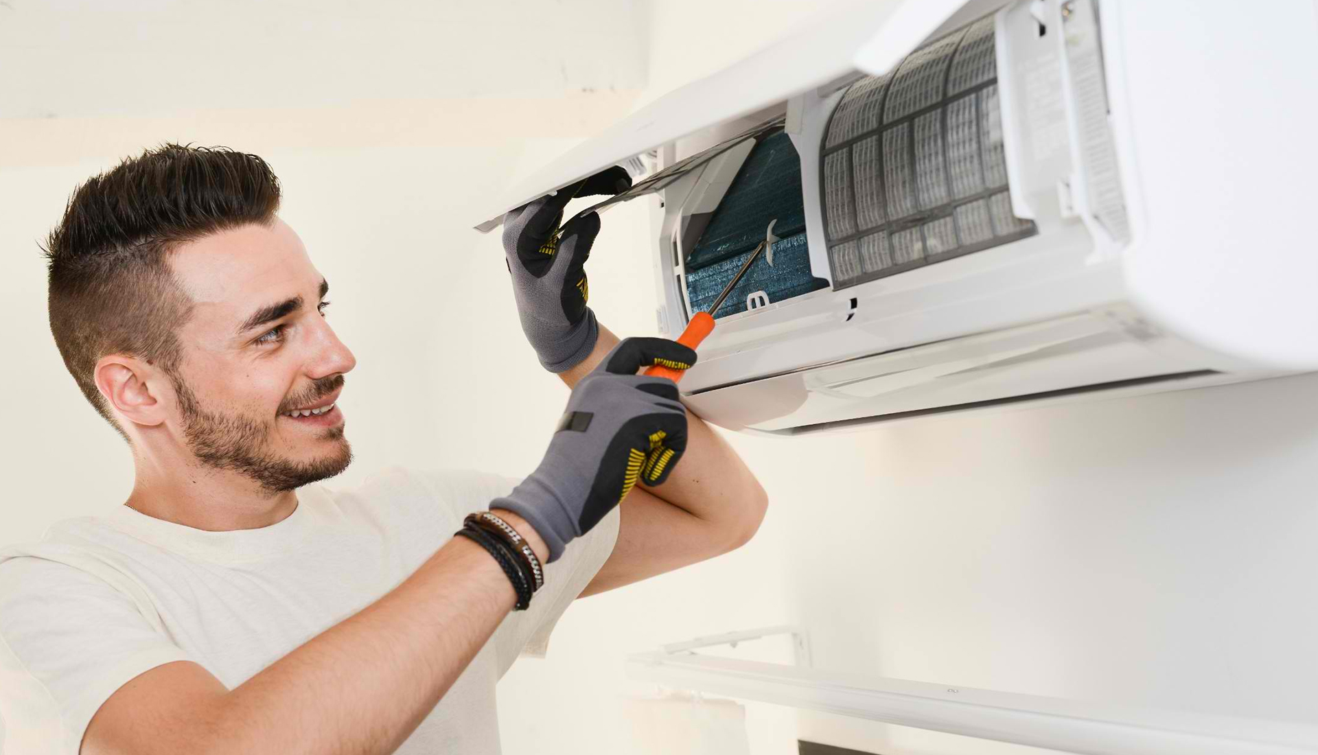 HVAC technician using screwdriver to repair & maintain split system air conditioning unit