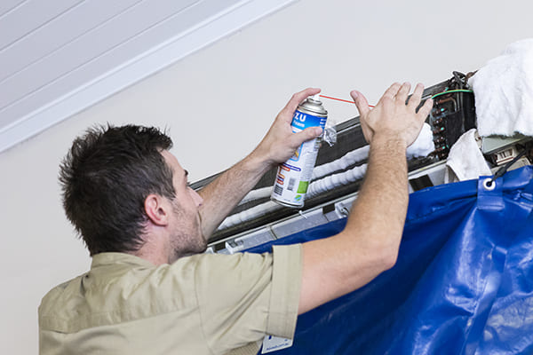 Technician cleaning split system air conditioner