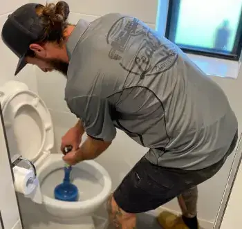 technician plunging a toilet