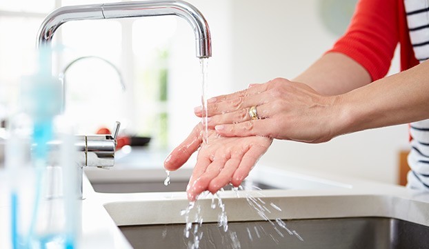 washing hands in kitchen sink under a running tap