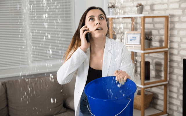 woman holding bucket under roof leak