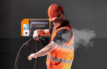 Man in PPE using a JetBlack Safety wall mounted personnel cleaning station to blow dust off his clothing