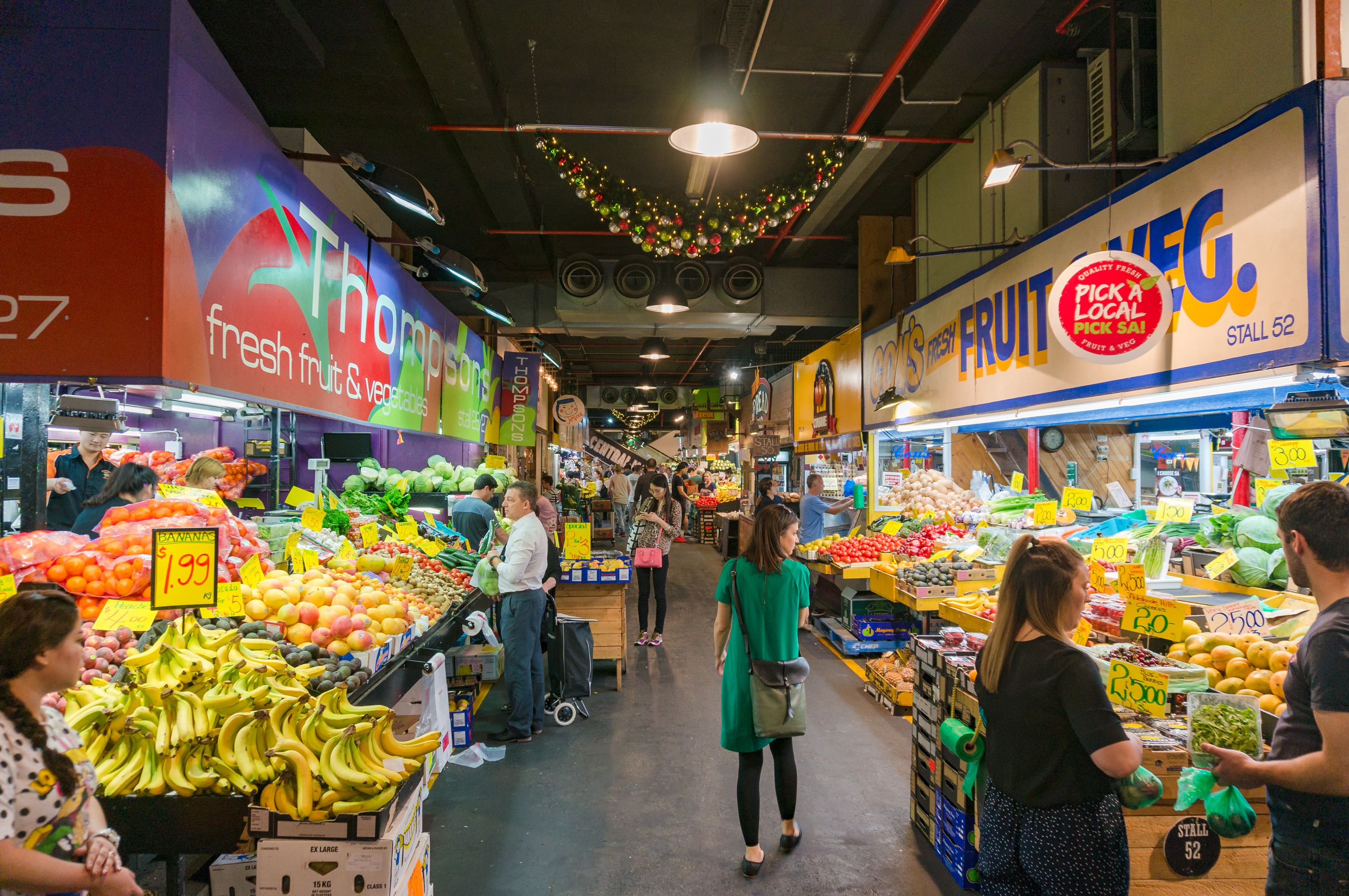 An aerial shot of Adelaide Central Market, revealing its vibrant atmosphere with rows of stalls offering fresh produce, spices, cheeses, and other gourmet delights.  