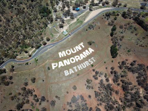The iconic Mount Panorama Motor Racing Circuit in Bathurst, surrounded by a panorama of historic architecture and cultural landmarks, reflecting the city's rich heritage. 