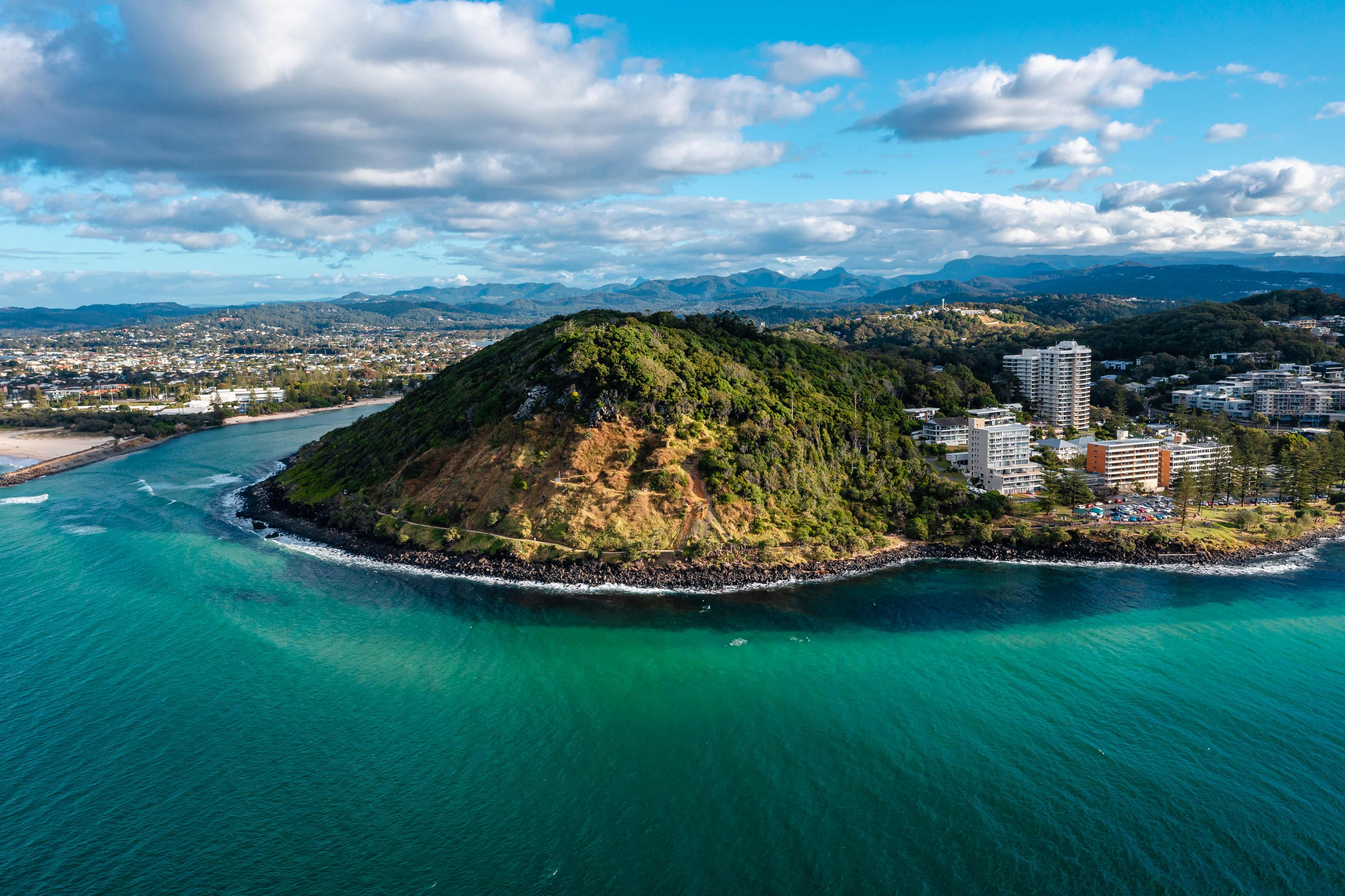 A scenic image of Burleigh Heads, capturing the surfers in action, the lush Burleigh Head National Park, and the relaxed beachside vibe. 