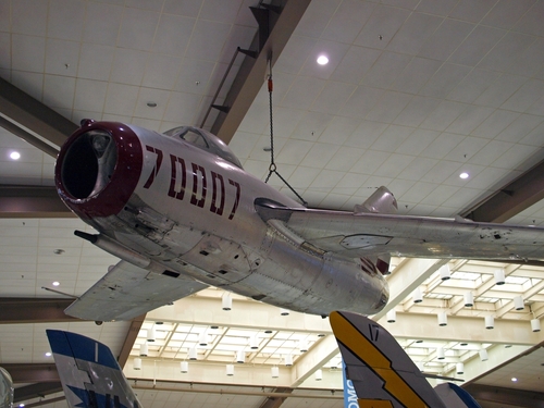 A dynamic image of the Classic Jets Fighter Museum displays an impressive array of historic jet aircraft in a spacious hangar. The focus is on a particularly well-restored fighter jet, with details of its sleek design and markings clearly visible, reflecting the meticulous care taken in its preservation. Visitors, including families and aviation enthusiasts, are seen admiring the aircraft, capturing the museum's appeal as a center for learning about and appreciating the advancements in military aviation technology and the bravery of those who piloted these 