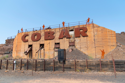 The rugged landscape of Cobar, showcasing its mining heritage with historic structures and equipment set against the backdrop of the vast Australian outback, illustrating the town's enduring connection to its rich mineral resources.