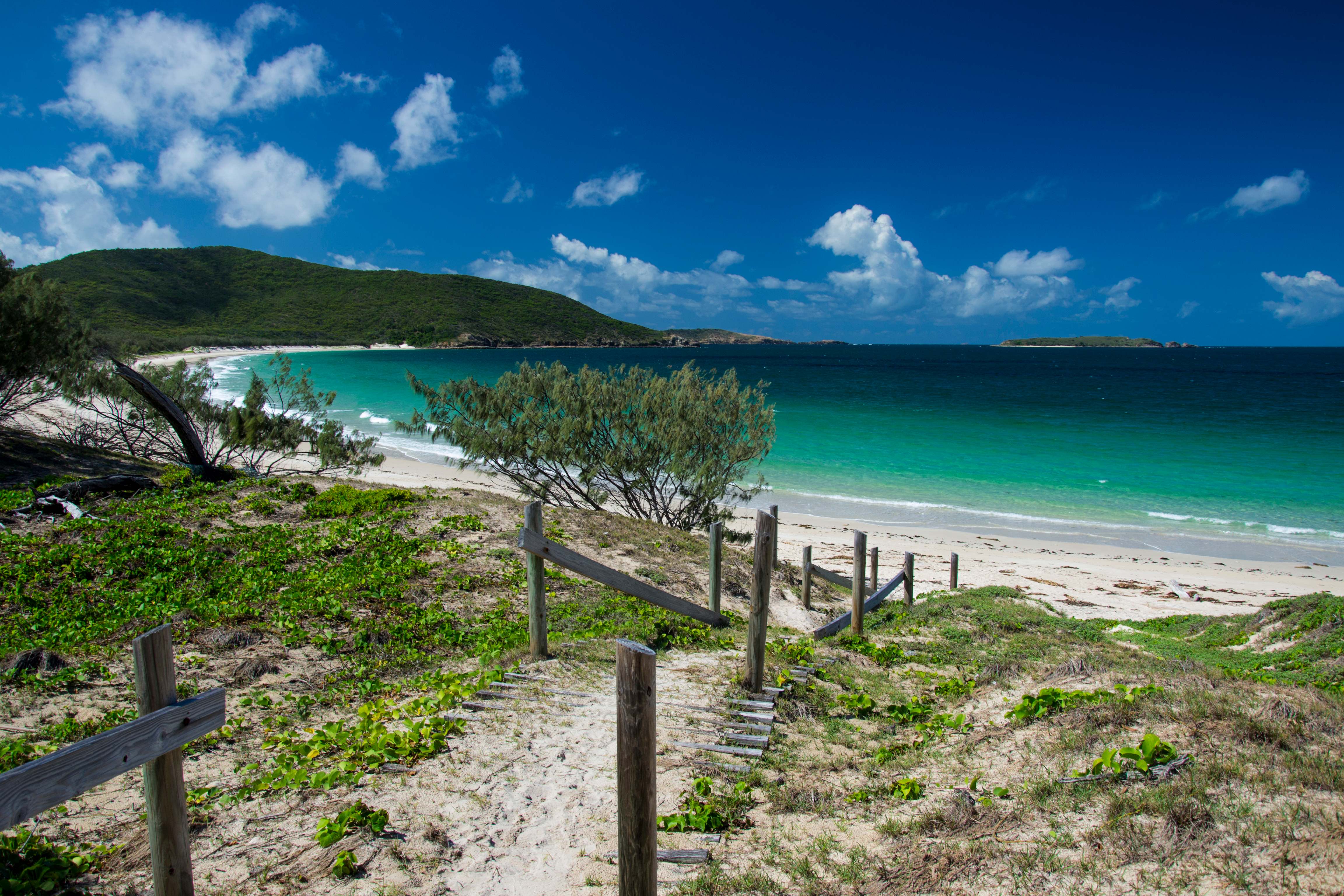 A scenic view of the crystal-clear waters surrounding Great Keppel Island, with white sandy beaches and coral formations visible beneath the surface. 