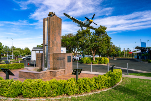 A scenic view of Griffith, showcasing its lush vineyards and productive farmlands, interspersed with symbols of its Italian heritage, illustrating the town's vibrant multicultural community and its success in agriculture and viticulture.
