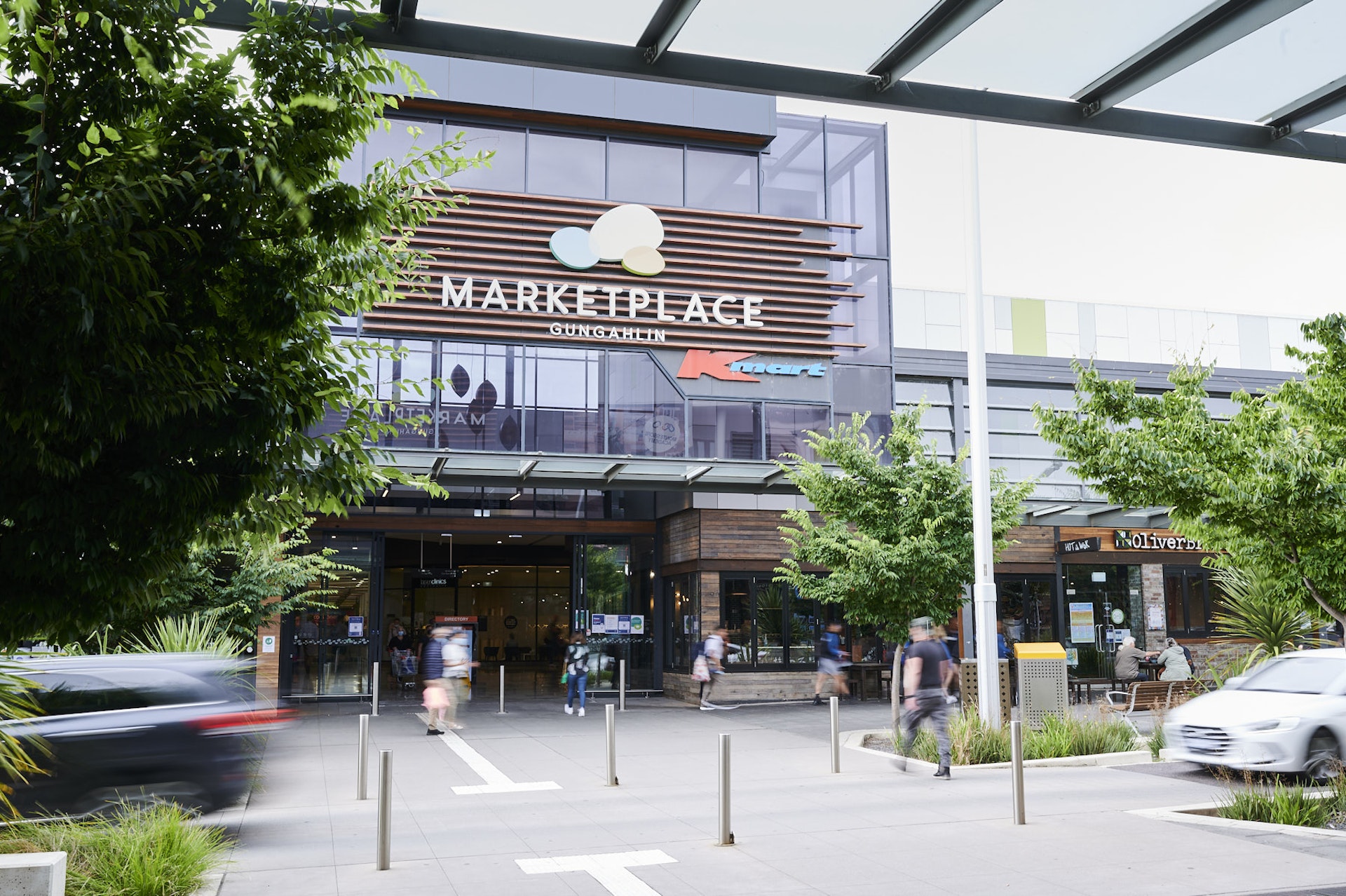 A vibrant streetscape of Gungahlin Town Centre, showcasing its modern architecture, bustling pedestrian activity, and diverse retail establishments. 