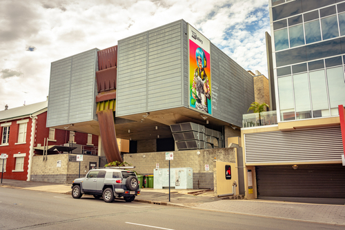 The exterior of the Ipswich Art Gallery is showcased, standing as a beacon of culture in the city. Its contemporary design hints at the creative and interactive exhibitions inside, designed for a wide audience from curious children to art aficionados. The welcoming entrance suggests a world where art is both fun and inspiring, emphasizing the gallery's role in making art universally accessible.