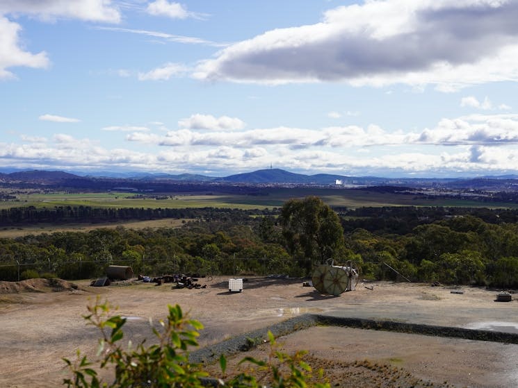 A captivating view from Jerrabomberra Lookout capturing the expansive landscape with rolling hills, verdant forests, and a winding river, all bathed in the warm glow of sunlight. 