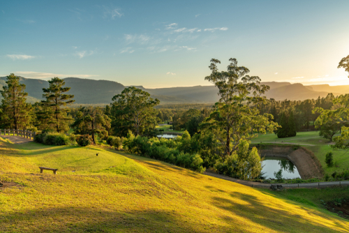 The scenic beauty of Kangaroo Valley, featuring its lush green hills, quaint historic village, and the tranquil Kangaroo River, reflecting the valley's charm and appeal for outdoor adventures and relaxation.