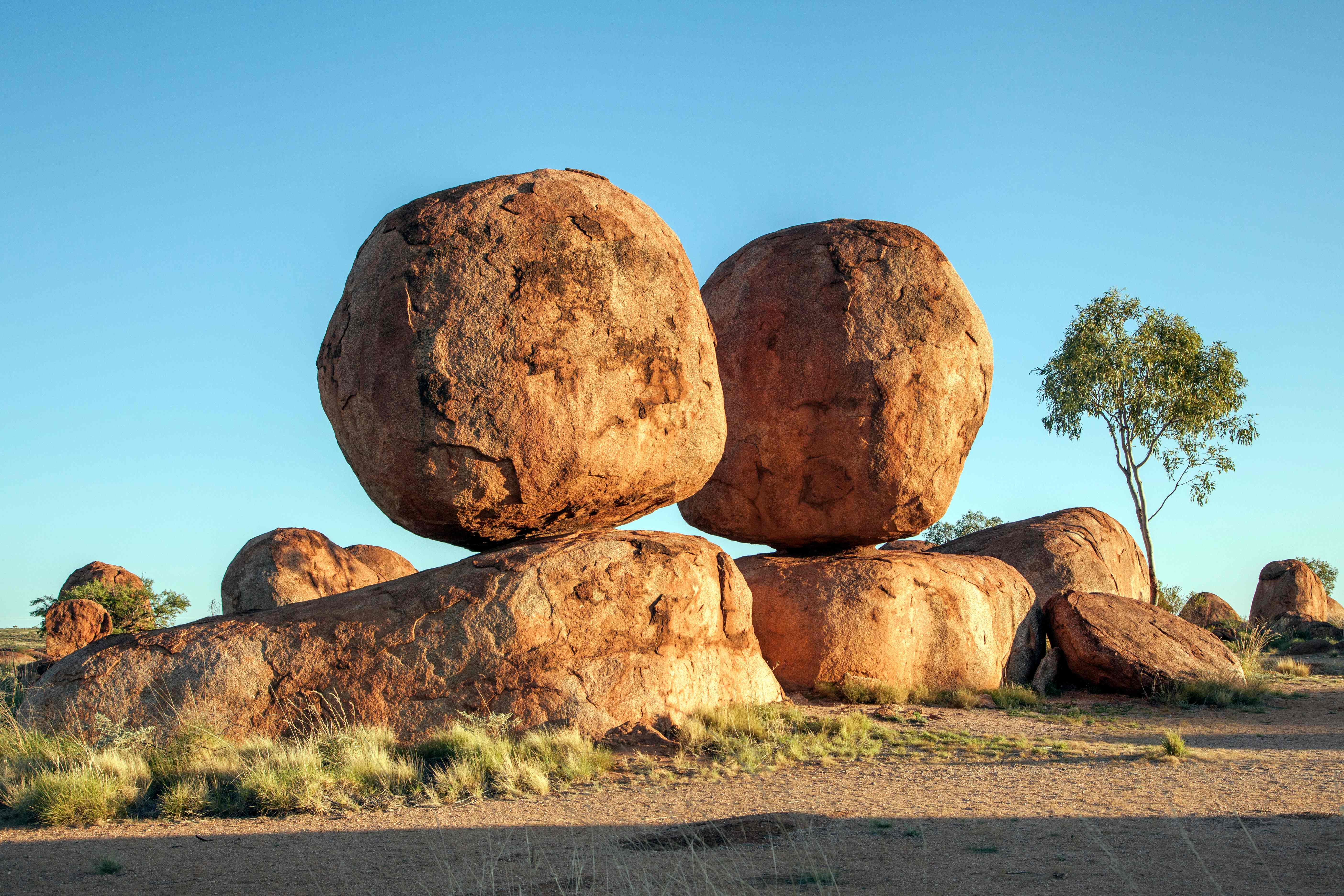 A photo of large granite boulders scattered across a desert landscape, with blue skies above 