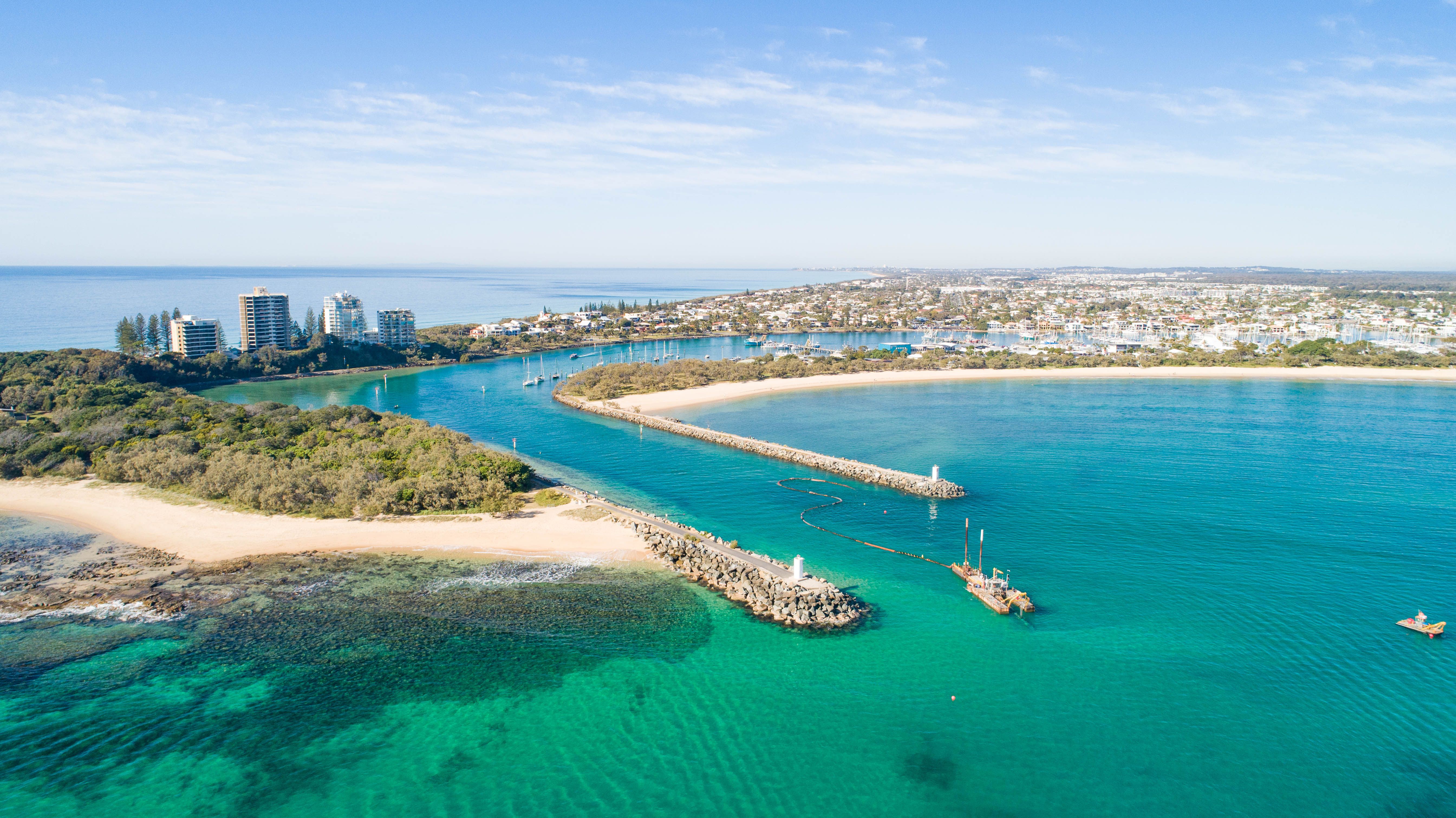 A lively scene from Mooloolaba Beach, with beachgoers enjoying the sun, surf, and beachfront cafes. 