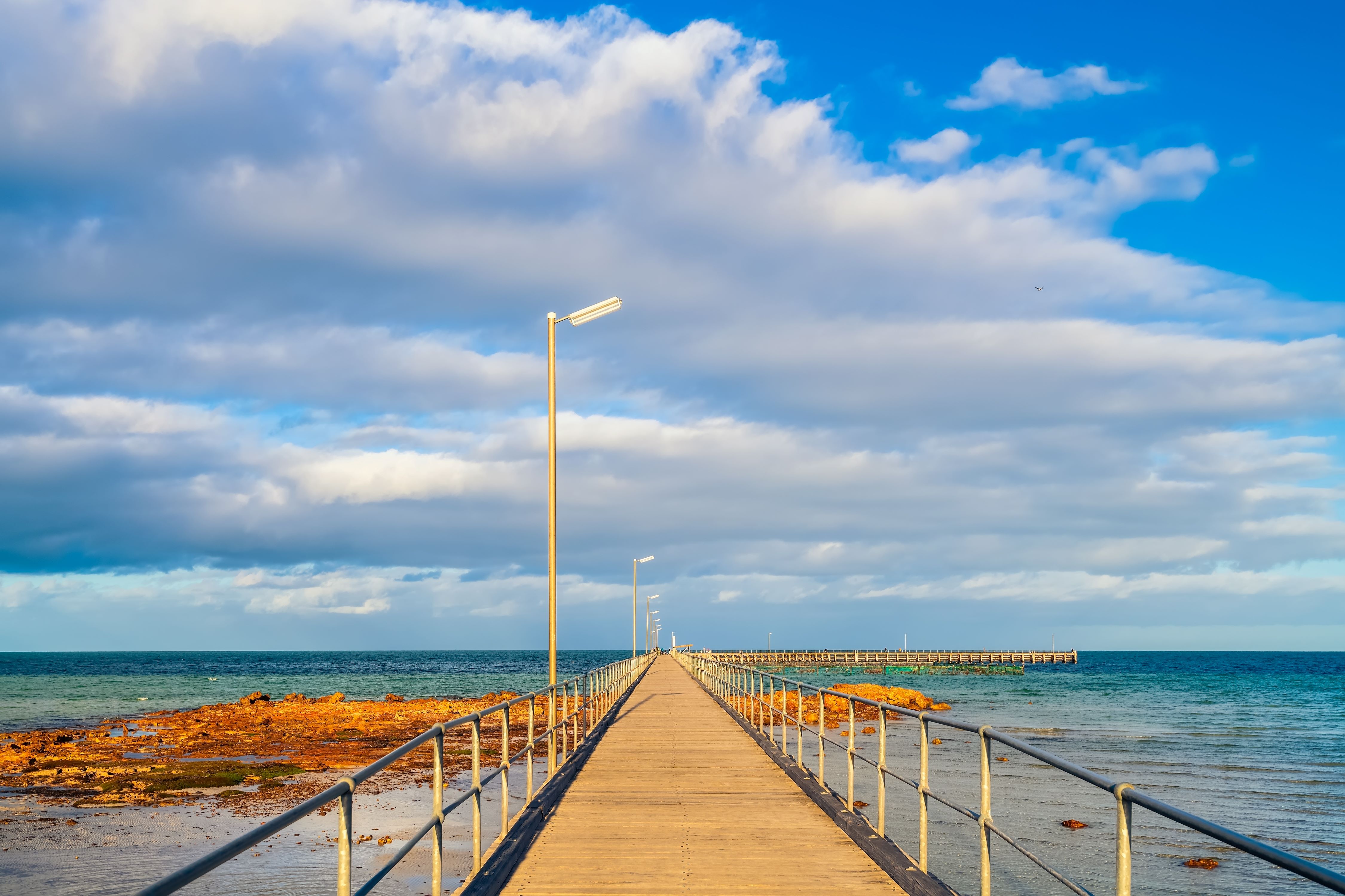 A wooden pier stretching into the calm waters, offering a picturesque spot for fishing and leisure activities. 