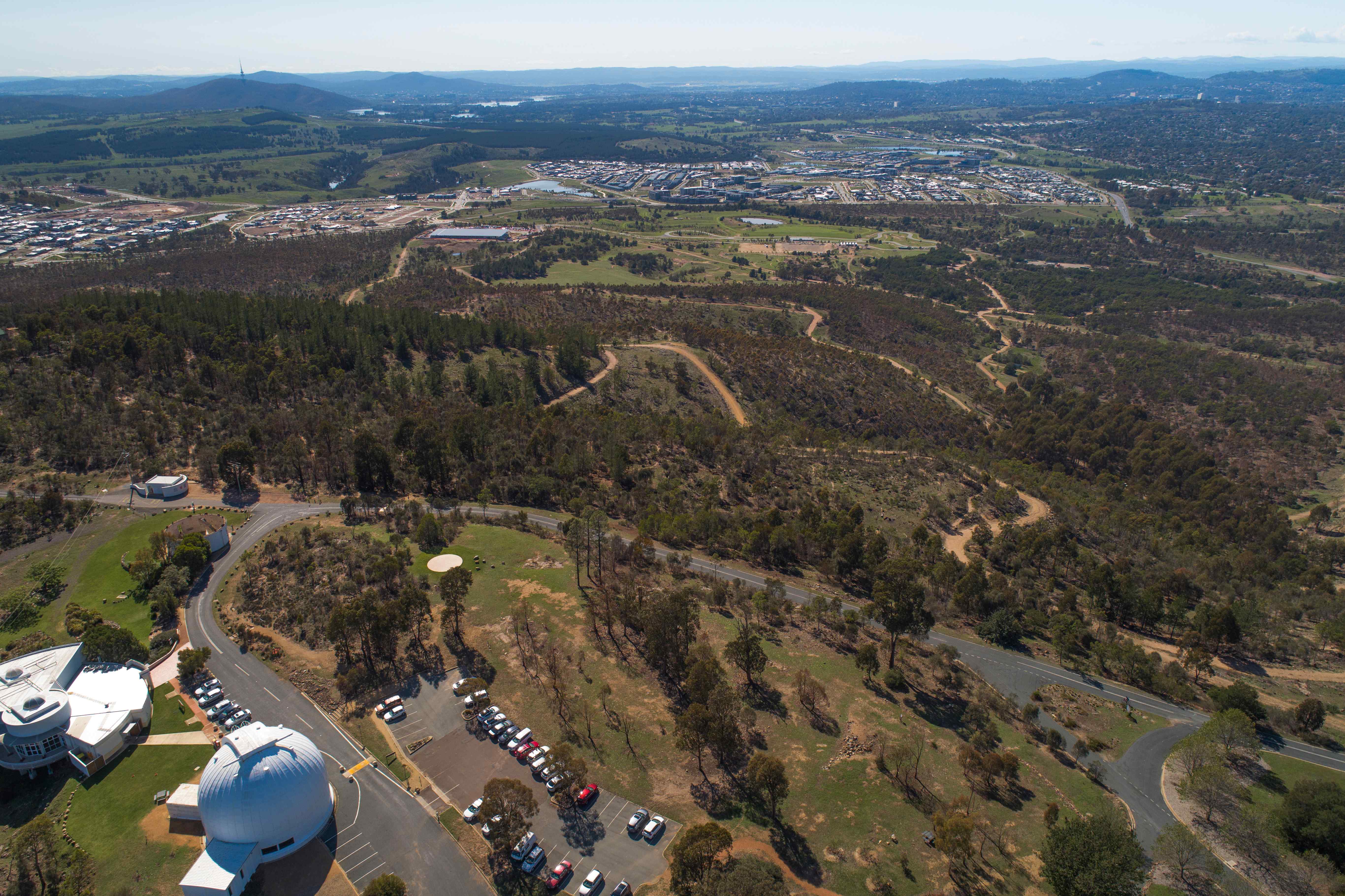 An awe-inspiring view of Mount Stromlo Observatory against the backdrop of a clear blue sky, with its domed telescopes and scientific equipment visible on the summit, highlighting its significance in astronomical research. 