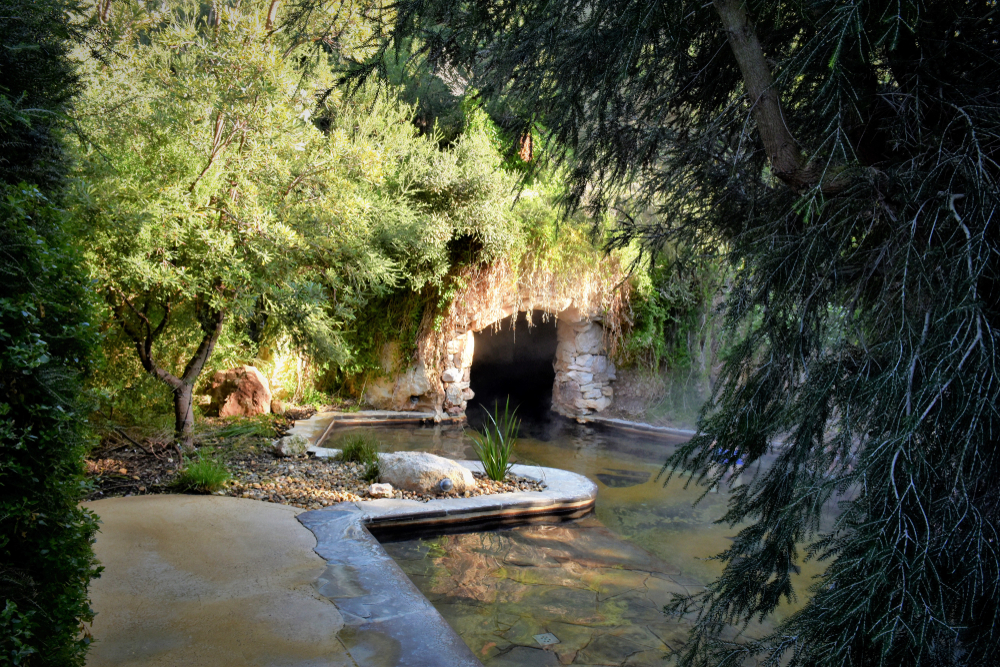 An image capturing the serene ambiance of Peninsula Hot Springs. The pools are terraced on a hillside, offering a peaceful escape and panoramic views of the surrounding area. Steam gently rises from the warm water, creating a mystical atmosphere that invites relaxation and wellness. This idyllic setting highlights the unique thermal experience available on the Mornington Peninsula, perfect for rejuvenation and natural therapy.