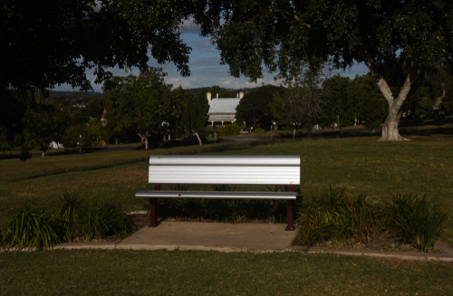 A tranquil oasis in the heart of Ipswich, Queens Park is captured in its full splendor, highlighting expansive lawns, mature trees, and vibrant flower beds under a clear sky. The image invites viewers into a peaceful retreat with the modern Nature Centre visible, where families engage with Australian wildlife, offering a blend of natural beauty and educational experiences.