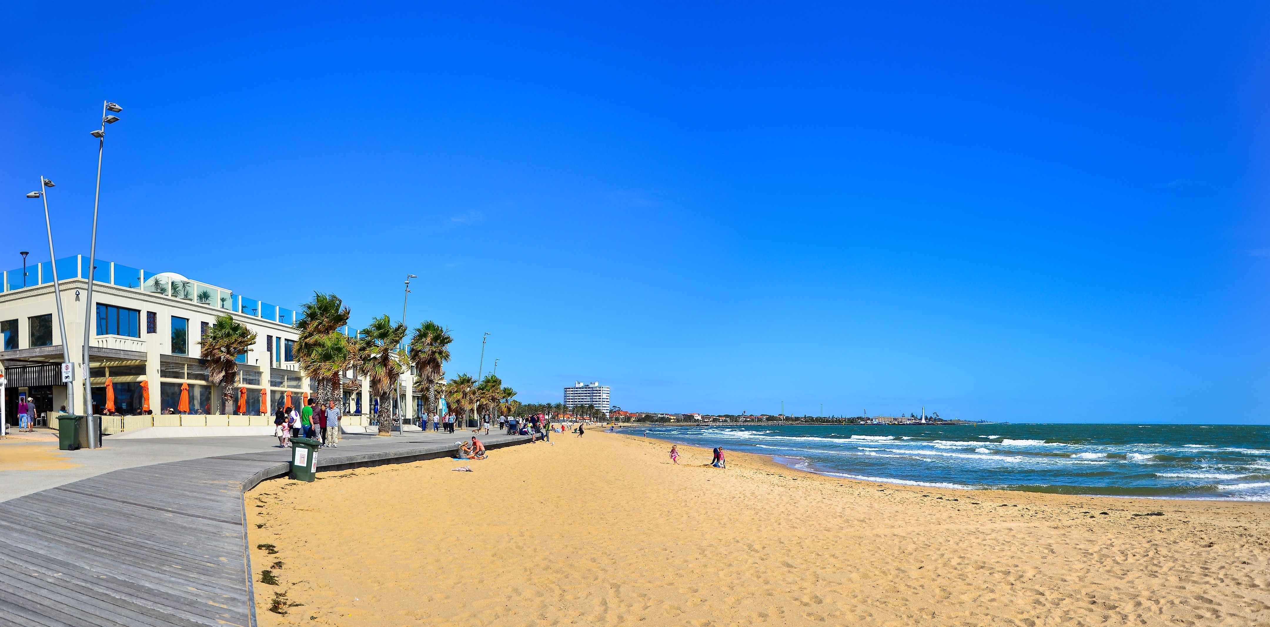 St Kilda Beach with beachgoers and the city skyline in the background. 