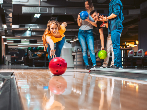 The vibrant interior of Strike Bowling Castle Hill, with lanes aglow in neon lights and groups of people enjoying a game of bowling. The atmosphere is electric, filled with laughter and competition, making it a hub of entertainment and social gathering in The Hills Area. 