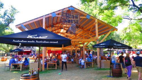 A vibrant and colorful scene from the Adelaide Fringe, showcasing a street filled with performers, artists, and spectators under the twinkling lights of evening festivities. The energy and creativity of the festival are palpable, highlighting Adelaide's status as a cultural epicenter, where the arts flourish in an atmosphere of inclusivity and celebration.