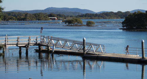 A serene aerial view of the Great Lakes, including Myall, Wallis, and Smiths Lake, showcasing their crystal-clear waters and surrounding lush greenery, a haven for water sports enthusiasts and nature lovers alike.