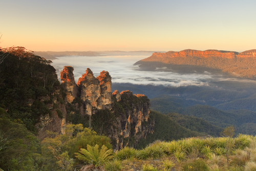 A captivating view of The Three Sisters, the majestic rock formation standing proudly at Echo Point, Katoomba, with the vast Blue Mountains panorama in the background, embodying both natural grandeur and cultural significance.