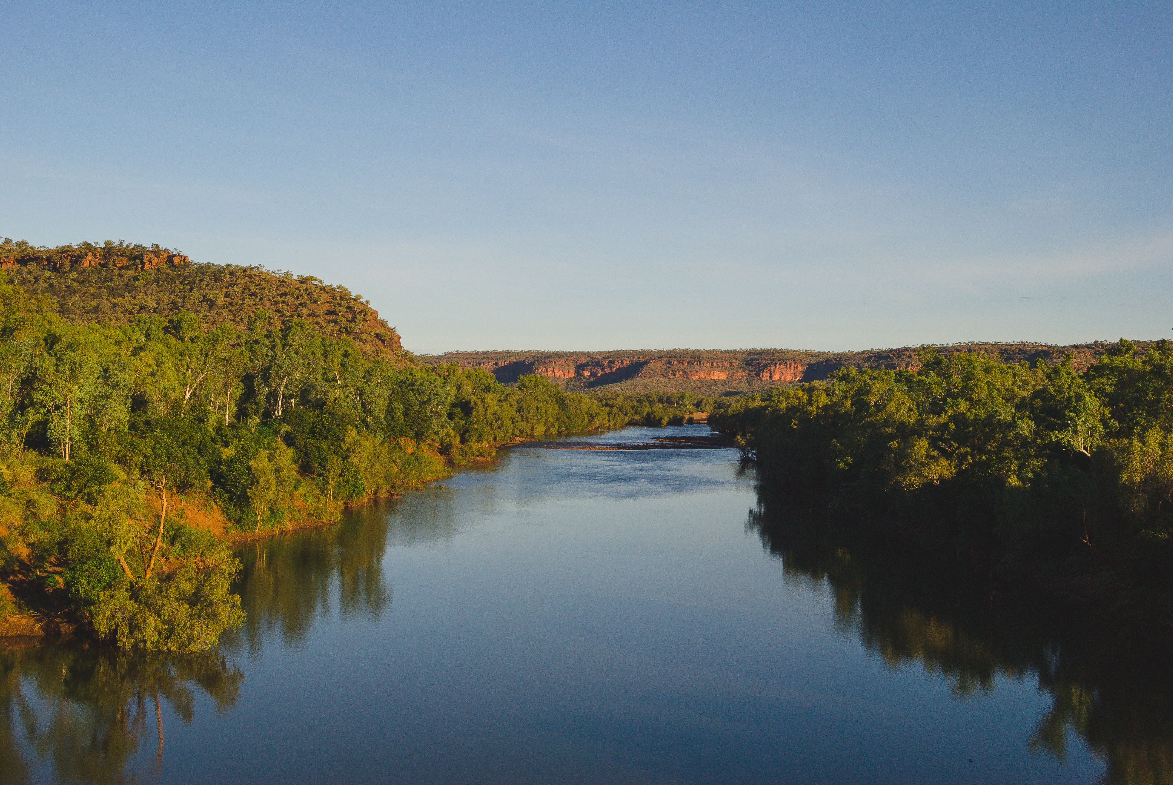 A photo of the Victoria River, with its meandering course cutting through red rocky cliffs and surrounded by lush vegetation. 