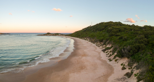 The sweeping vistas of Wollongong's beaches, where the golden sands meet the sparkling blue of the Pacific Ocean. Surfers carve through the waves, and families enjoy the sunshine, capturing the essence of Wollongong's coastal charm.