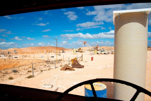 The unique landscape of Coober Pedy, dotted with mining shafts and machinery, illustrating its status as the opal capital of the world, a treasure trove of this precious gemstone.