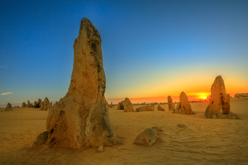 The enigmatic Pinnacles standing tall in the golden sands of Nambung National Park, their striking limestone formations creating a surreal and mysterious landscape.