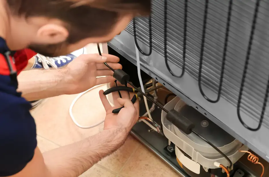 Sea Air refrigeration mechanic using pliers to perform repairs on a fridge