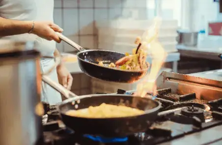 chef cooking on a large commercial gas stove